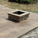 Square stone fire pit on concrete patio.